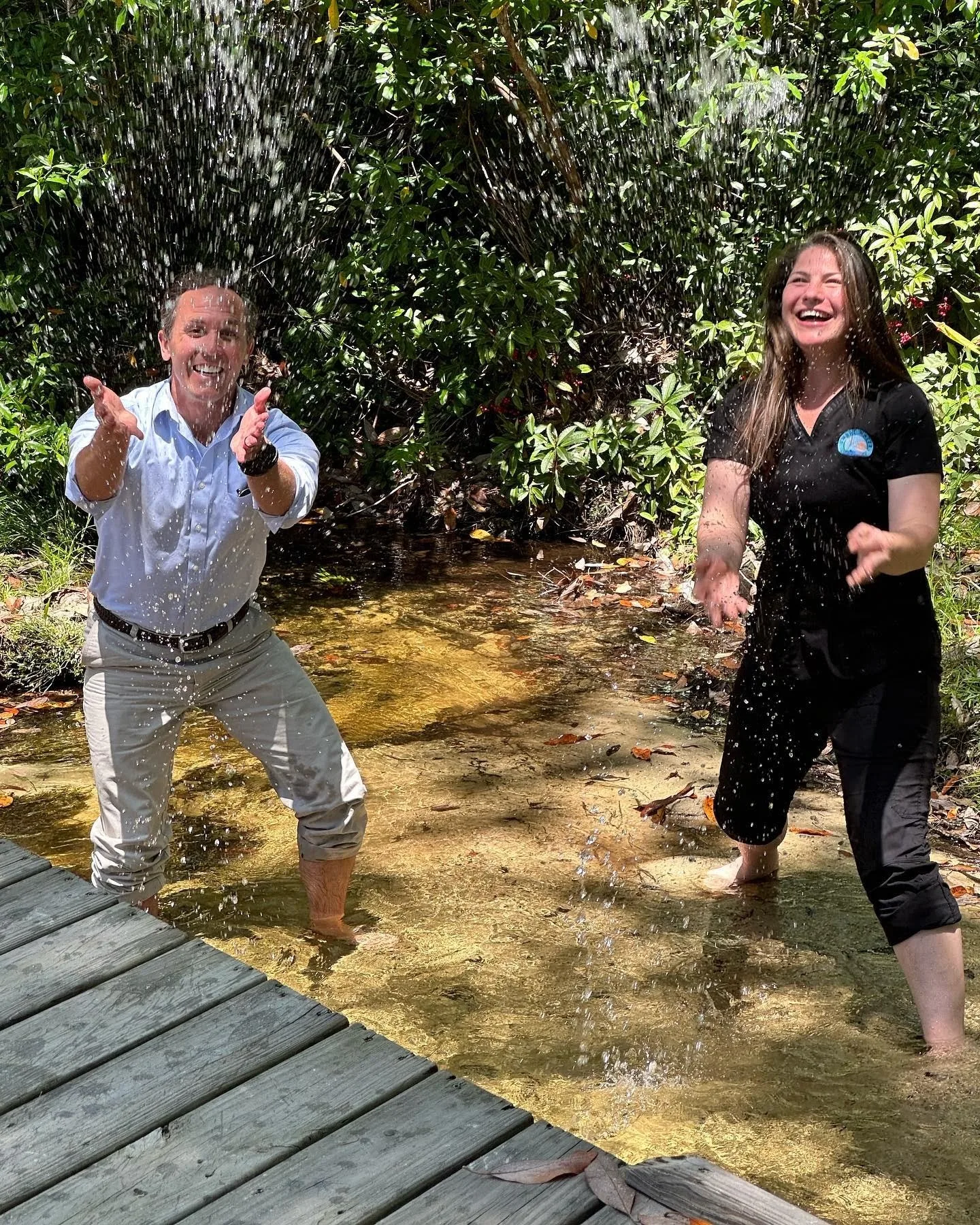 Dr. Greer and a team member splashing in the cold-water spring behind the office
