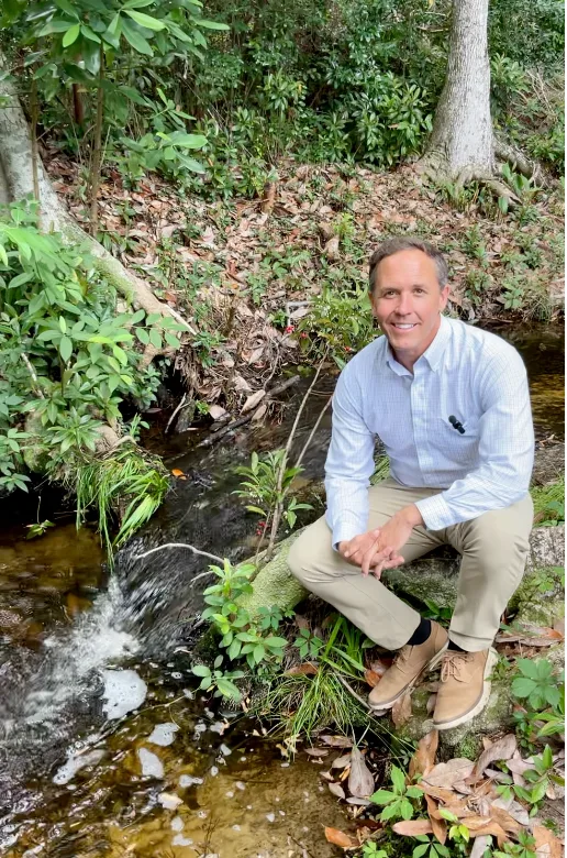 Dr. Greer sitting beside the flowing spring